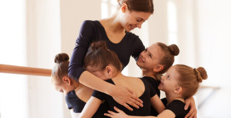 Young dancers hug their beloved dance teacher in their local dance studio