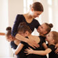 Young dancers hug their beloved dance teacher in their local dance studio